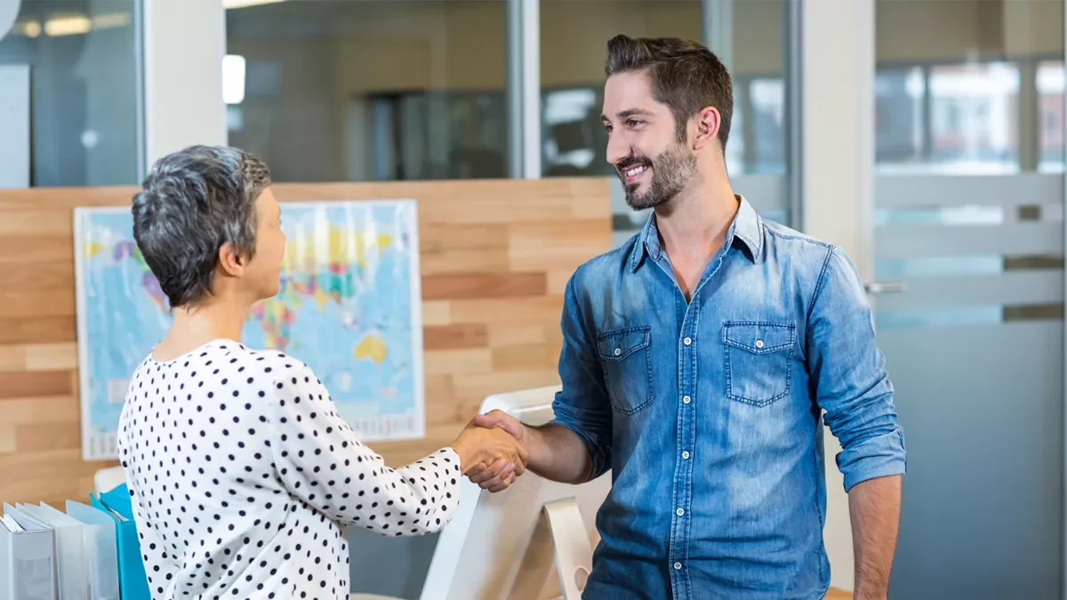 A local web developer shakes hands with a client in a modern office setting, representing trust and collaboration in web development services.
