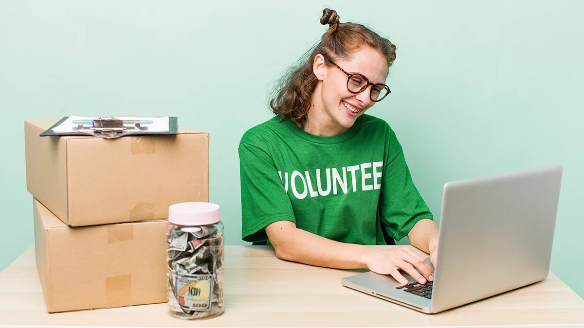 Volunteer working on a laptop beside donation supplies, representing how a nonprofit web designer empowers organizations with user-friendly digital tools for fundraising and engagement.