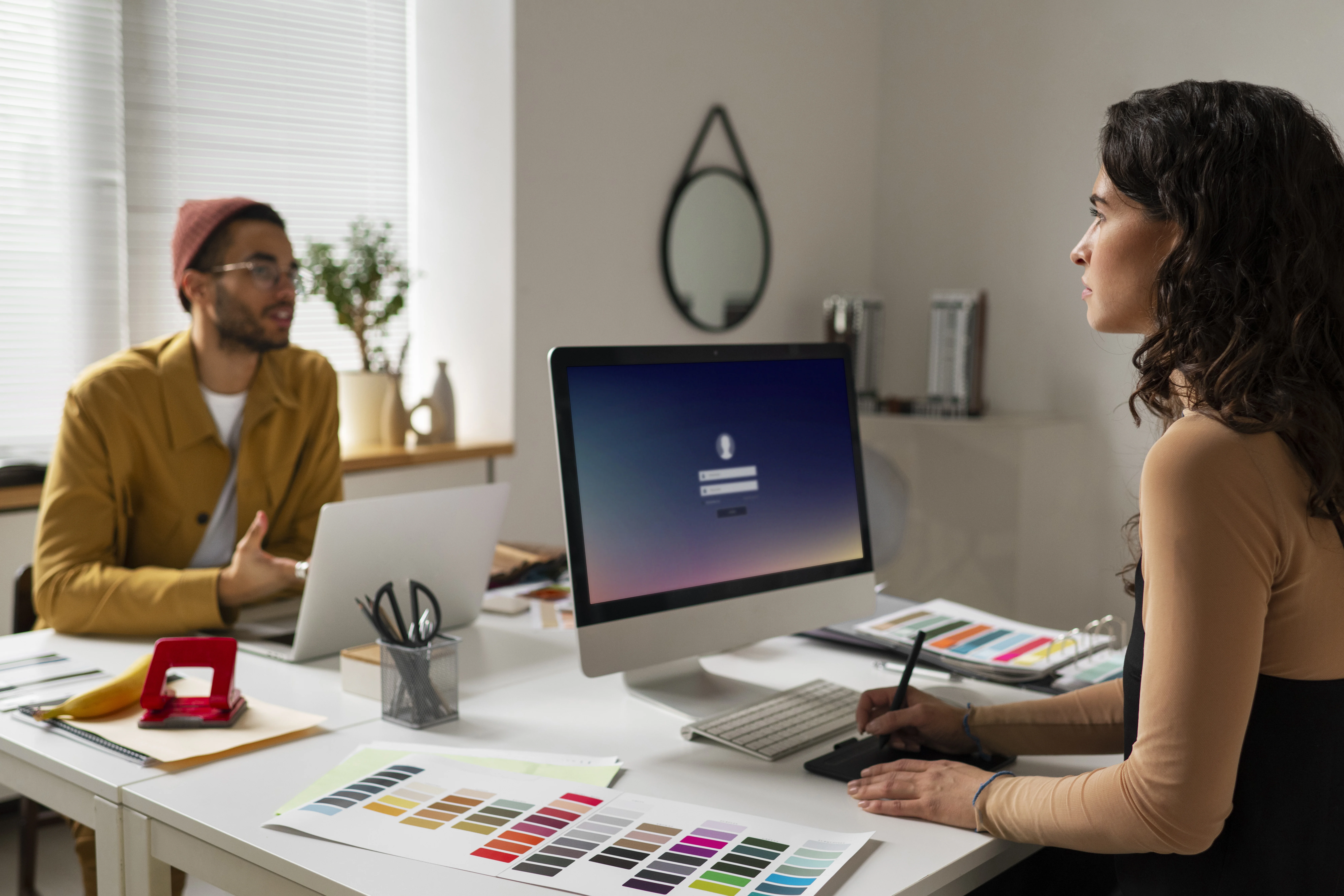 Web developers collaborating in a modern office, reviewing UI design elements and color palettes on desktop computers